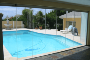 Frameless glass stacking doors seperating the home from the pool in the garden